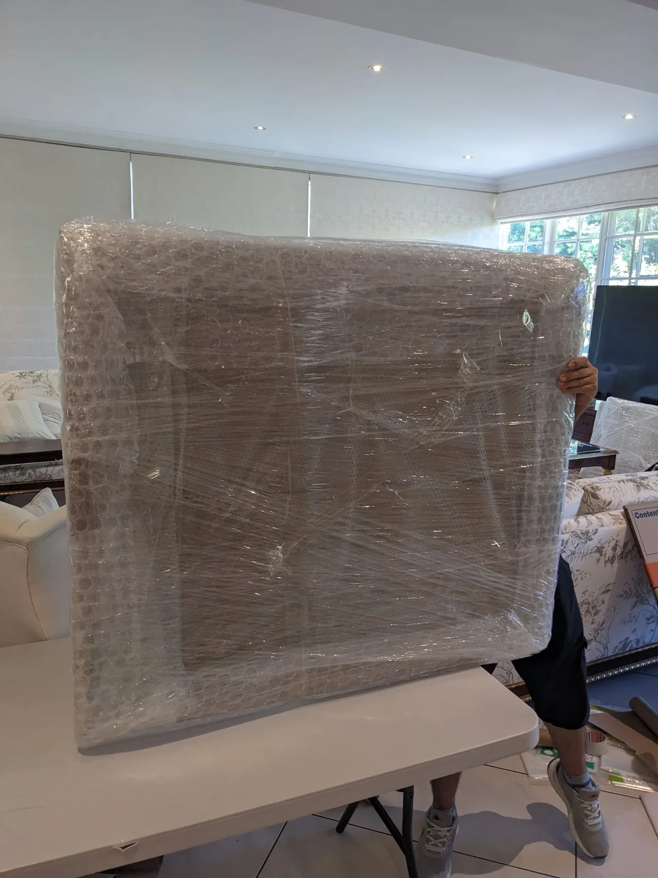 Wrapped furniture carried through a living space